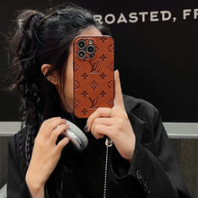 Three Louis Vuitton branded phone cases in black, blue, and orange with embossed monogram patterns, each housing a different model of iPhone.