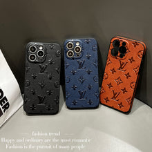 Three Louis Vuitton branded phone cases in black, blue, and orange with embossed monogram patterns, each housing a different model of iPhone.